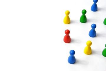Game figures from a board game in different colors stand on a white background and throw all the shadows in one direction - concept with different figures on white background