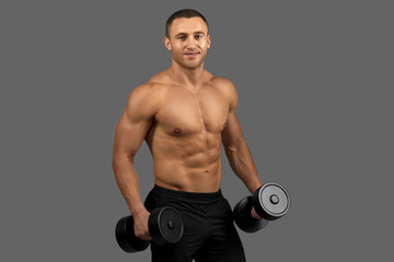 Fototapeta na wymiar Sexy man with muscular torso posing, holding dumbbells.