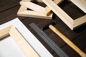 Tools for canvas stretching on wooden stretcher bar. Hammer and steel ruler on brown table