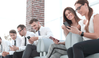 Fototapeta premium group of employees with gadgets sitting in the office waiting room