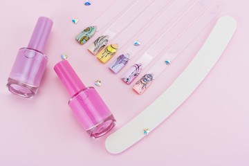 Nail designs on tips and manicure set on a pink background.Wide photo with free space for text.