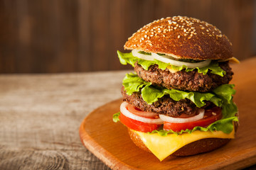 Tasty burger with cheese on wooden table