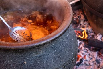 Preparing food outdoor for many people, direct on fire in a big pot.