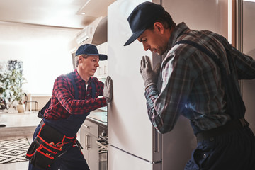 Easy to solve. Young men mechanics checking refrigerator