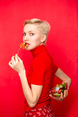 Beautiful caucasian woman eating salad over red background