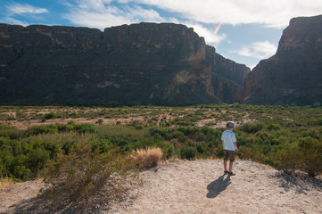 a small boy standing in front of  mountain wall in a Big Bend National Park, Texas