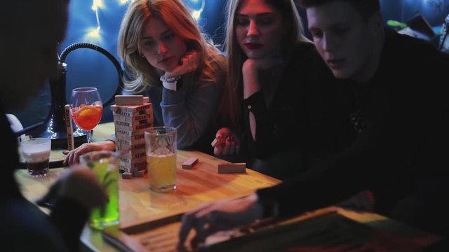 Friends plays backgammon in a blue bar