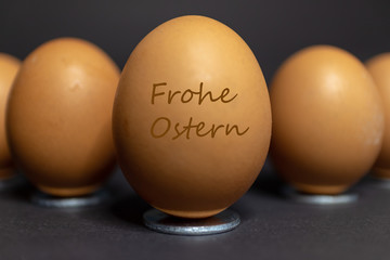 Anordnung von mehreren Eiern für Ostern vor schwarzen Hintergrund.Mit dem Text Frohe Ostern in deutscher Sprache.