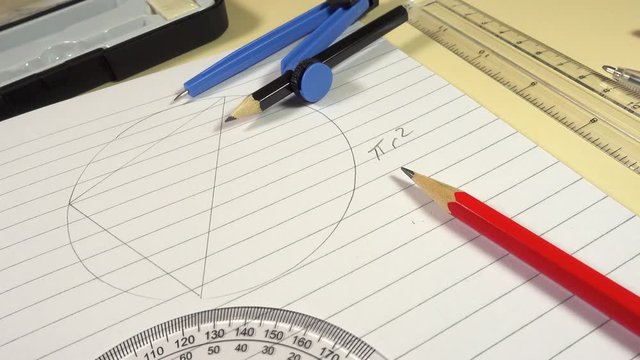 Track up over an exercise book and geometry set on a school desk.