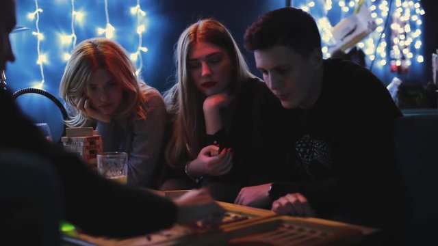 Friends plays backgammon in a blue bar
