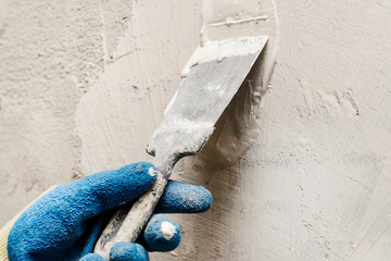 girl in blue gloves. review only a limb. putty putty on the wall. close-up