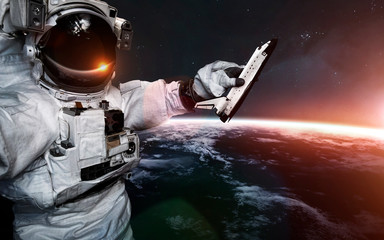 Astronaut with toy Shuttle in his hand. Science fiction art. Elements of this image furnished by NASA
