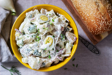 Traditional American potato salad with egg and mayonnaise, served with bread. Rustic style.
