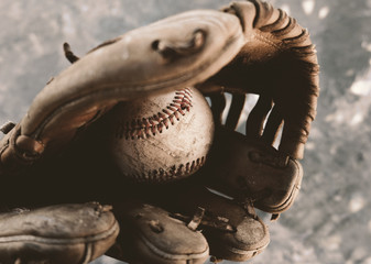 Old baseball in leather glove close up with grunge style image.