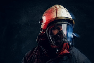 Close-up portrait of a firefighter in safety helmet and an oxygen mask in dark studio