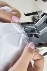 sewing process on sewing professional manufacturing machine with metal needle detailed by white caucasian woman's hands holding lace fabric for lingerie production