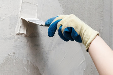 girl in blue gloves. review only a limb. putty putty on the wall. close-up