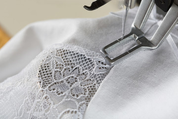 sewing process on sewing professional manufacturing machine with metal needle detailed by white caucasian woman's hands holding lace fabric for lingerie production