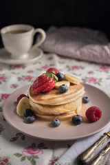 Delicious american pancakes with berries, banana and syrup. Vertical