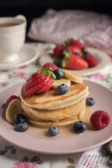 Delicious american pancakes with berries, banana and syrup. Vertical. Closeup