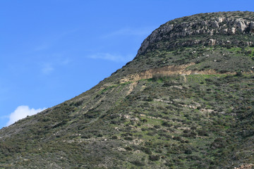 Green hill in front of blue sky