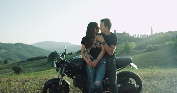 Romantic couple in a blurred images spending good time together in the middle of nature , beside motorcycle