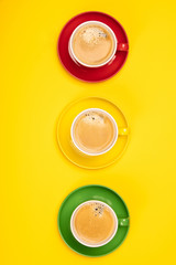 Colorful cups of coffee on yellow background