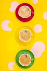 Cups of Coffee and colorful paper circles on yellow paper background