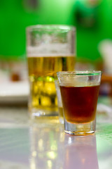 Detail of a tabel with liquor glass and beer glass. Green background. Feira de Sao Cristovao, Rio de Janeiro, Brazil. 2017