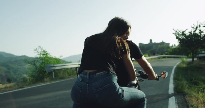 Young couple standing their ride on the big Bugatti monster motorcycle in the middle of motorway