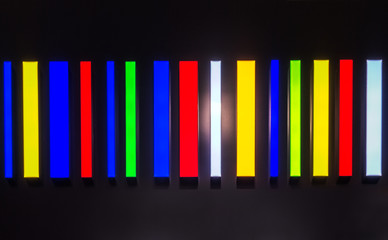 energy saving lamps of different colors on the black surface abstract background texture