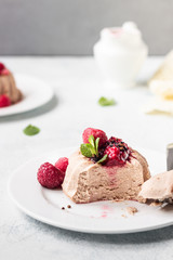 Two mini chocolate cheesecake with raspberry sauce and mint. No crust cheesecake. Diet dessert. Light grey stone concrete background. Copy space.