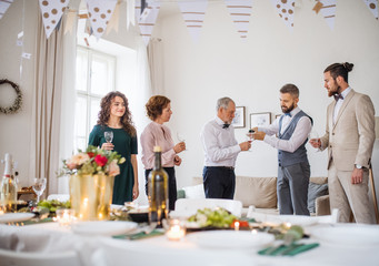 A man pouring guests wine on a indoor family birthday party.