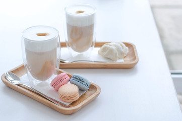 Two latte cups with macaroons and cookies.