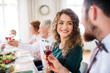 A young couple sitting at a table on a indoor birthday party, clinking glasses.