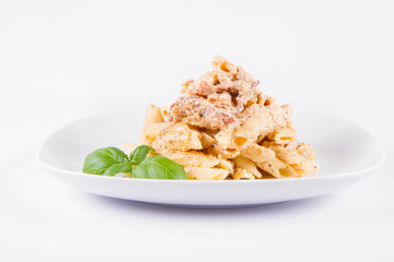 Pasta - penne with white cream sauce with bacon on a plate, decorated with fresh basil