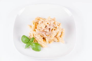Pasta - penne with white cream sauce with bacon on a plate, decorated with fresh basil