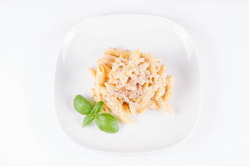 Pasta - penne with white cream sauce with bacon on a plate, decorated with fresh basil