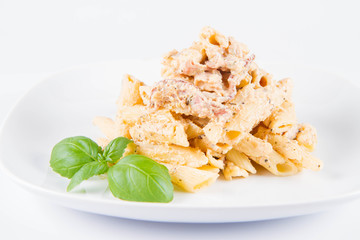 Pasta - penne with white cream sauce with bacon on a plate, decorated with fresh basil	