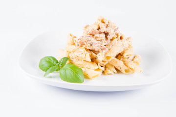 Pasta - penne with white cream sauce with bacon on a plate, decorated with fresh basil
