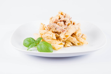 Pasta - penne with white cream sauce with bacon on a plate, decorated with fresh basil