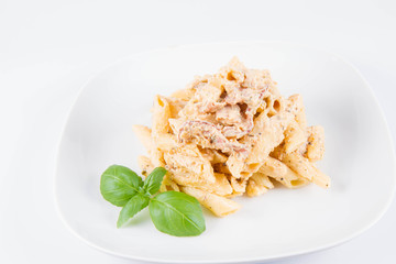 Pasta - penne with white cream sauce with bacon on a plate, decorated with fresh basil