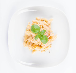 Pasta - penne with white cream sauce with bacon on a plate, decorated with fresh basil