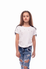 Obraz premium Studio shot of a little serious girl wearing jeans and white blouse on a white background. She is going
