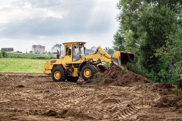 large yellow wheel loader aligns a piece of land for a new building