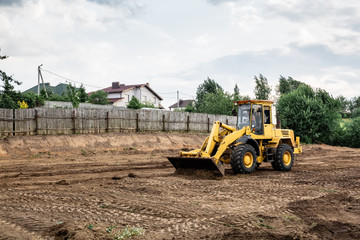 large yellow wheel loader aligns a piece of land for a new building © Hanna