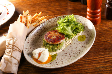 Pashto egg with cutlet and salad on plate and black wood background 