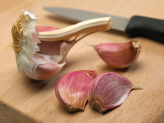 GARLIC BULB AND CLOVES ON WOODEN CHOPPING BOARD WITH KITCHEN KNIFE
