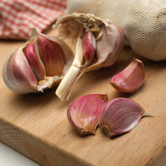 GARLIC BULB AND CLOVES ON WOODEN CHOPPING BOARD