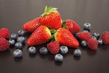 Obraz na płótnie Canvas Berry mix. Strawberries, blueberries and raspberries on black wooden background